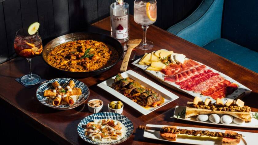 Mesa con paella, jamón, quesos y tapas variadas para compartir