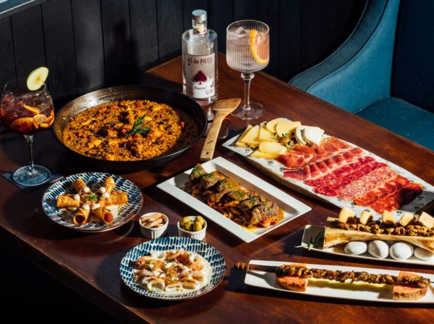 Mesa con paella, jamón, quesos y tapas variadas para compartir