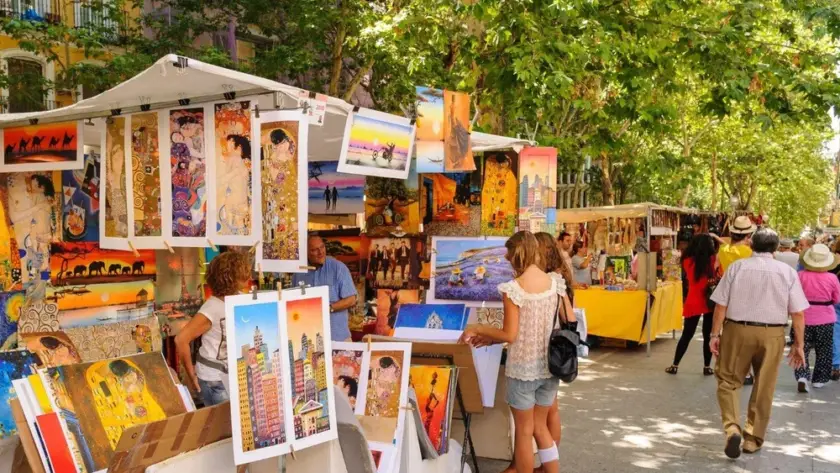 Puestos de un mercado de arte al aire libre en Madrid bajo los árboles