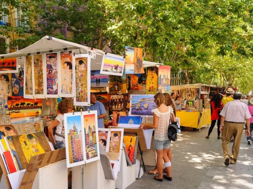 Puestos de un mercado de arte al aire libre en Madrid bajo los árboles
