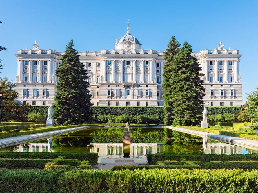Fachada del Palacio Real de Madrid y sus jardines con estanque en un día despejado