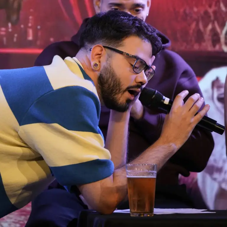 Cómico con gafas y polo de rayas hablando muy cerca del micrófono