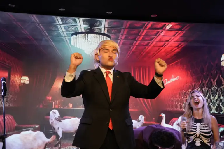 Artista con traje y peluca rubia levantando los dos puños en el escenario