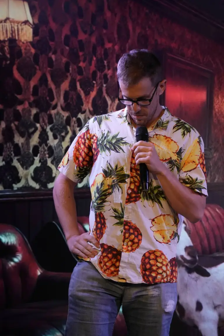Cómico con camisa de estampado de piñas mirando hacia el micrófono