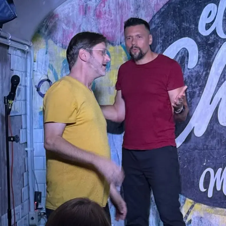 Dos artistas con camisetas amarilla y roja representando una escena