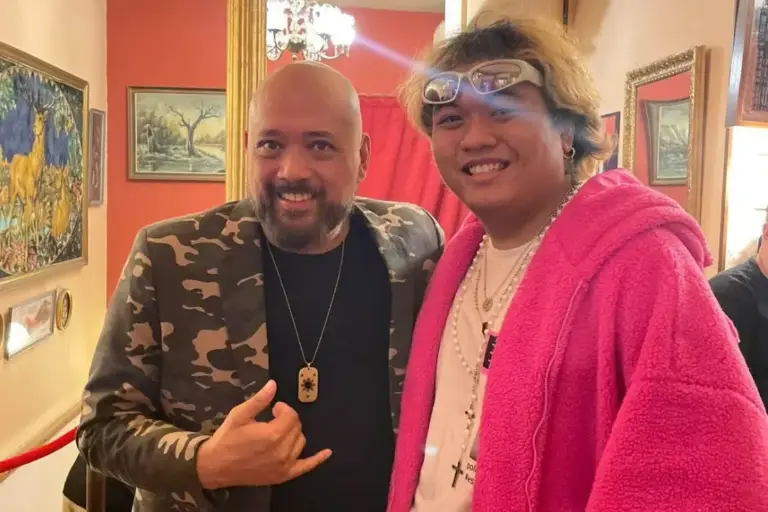 Dos cómicos posando juntos, uno con forro polar rosa