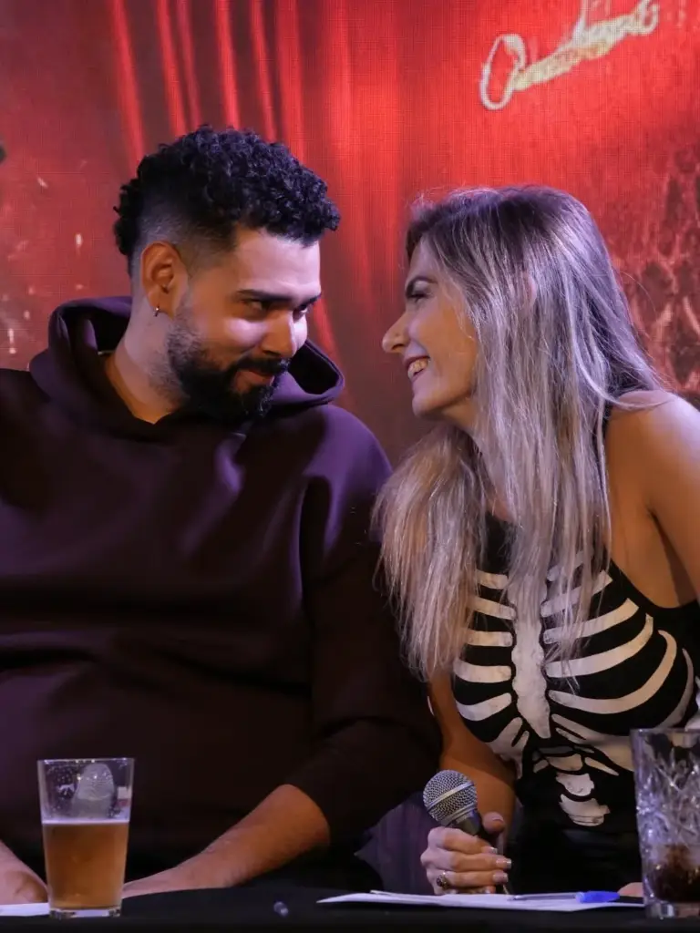 Dos artistas sentados en el escenario riéndose juntos