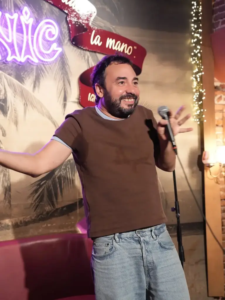 Cómico con camiseta marrón con los brazos abiertos en el escenario de Picnic
