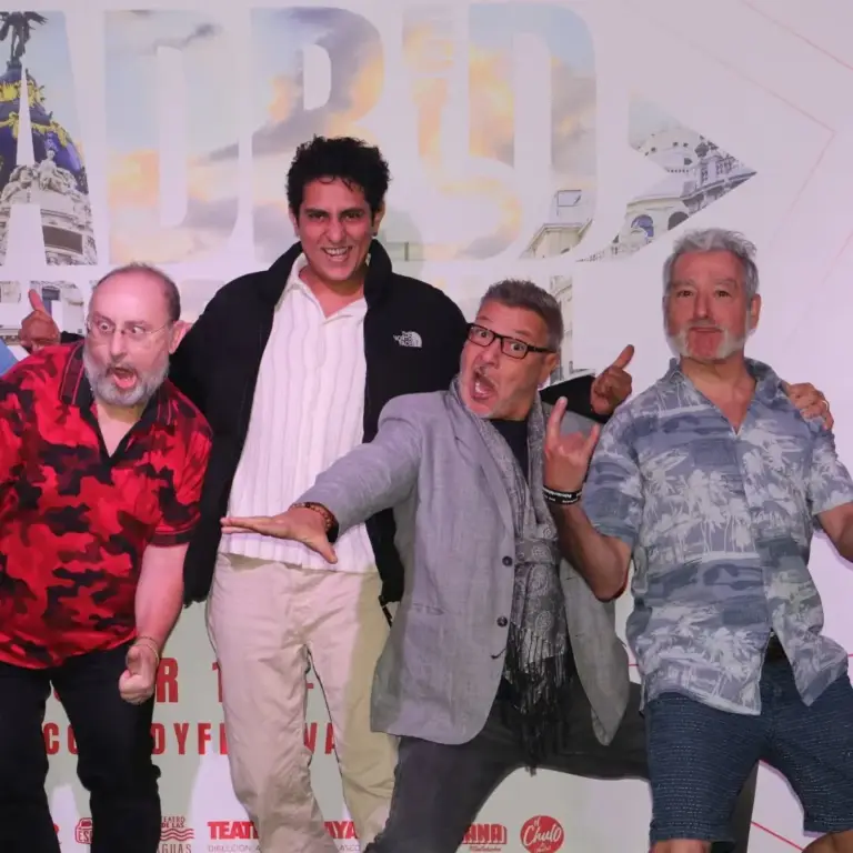 Cinco hombres posando en broma delante del cartel del festival en la presentación a medios