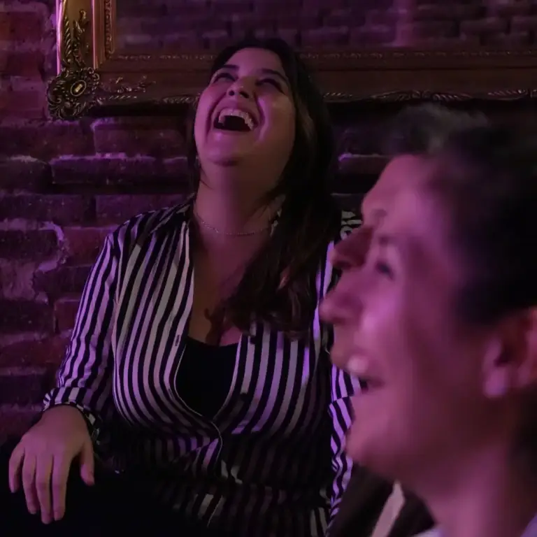 Mujer con top de rayas riéndose a carcajadas entre el público