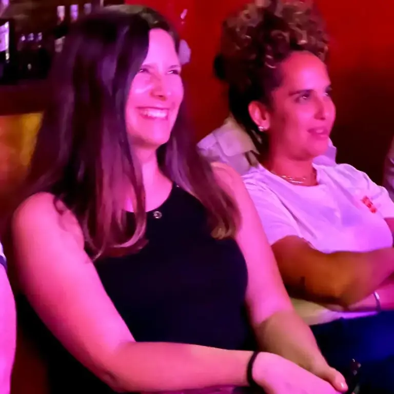 Dos mujeres del público sonriendo bajo luz roja