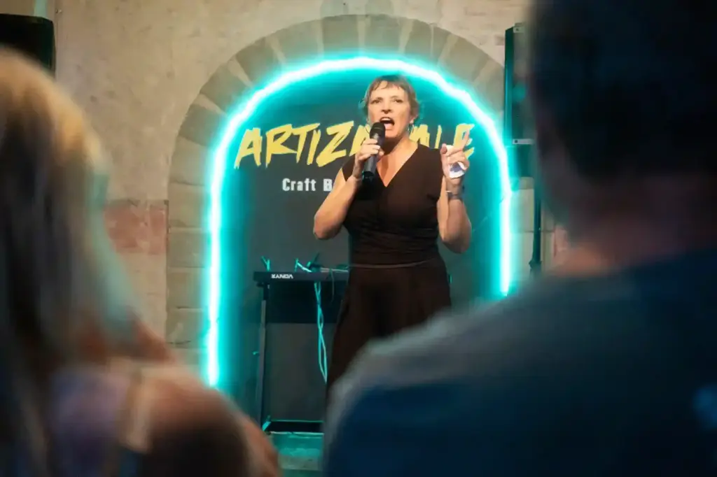 Cómica actuando bajo el arco de neón de Artizanale en la Gala de Clausura