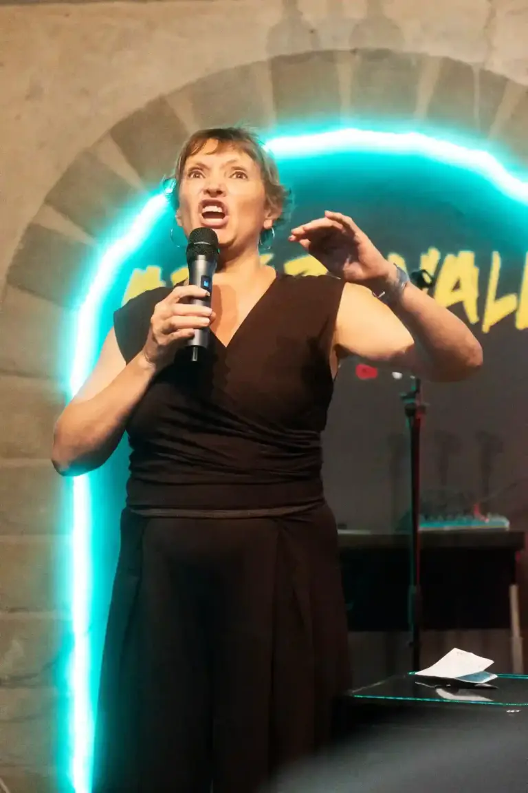 Cómica con vestido negro gesticulando mientras cuenta una historia en Artizanale