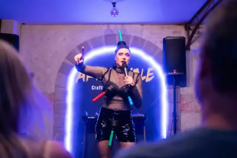 Artista con medias de rejilla y un tocado alto en el escenario de Artizanale