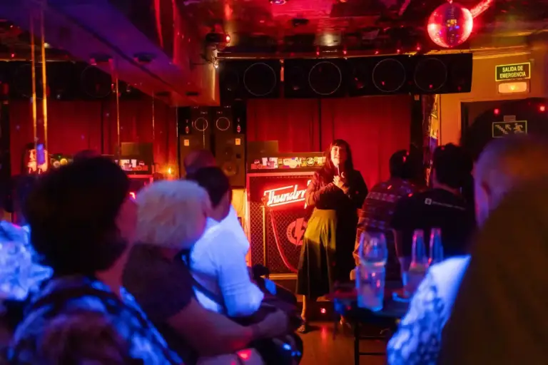 Artista actuando en una sala pequeña con luz roja y llena de público