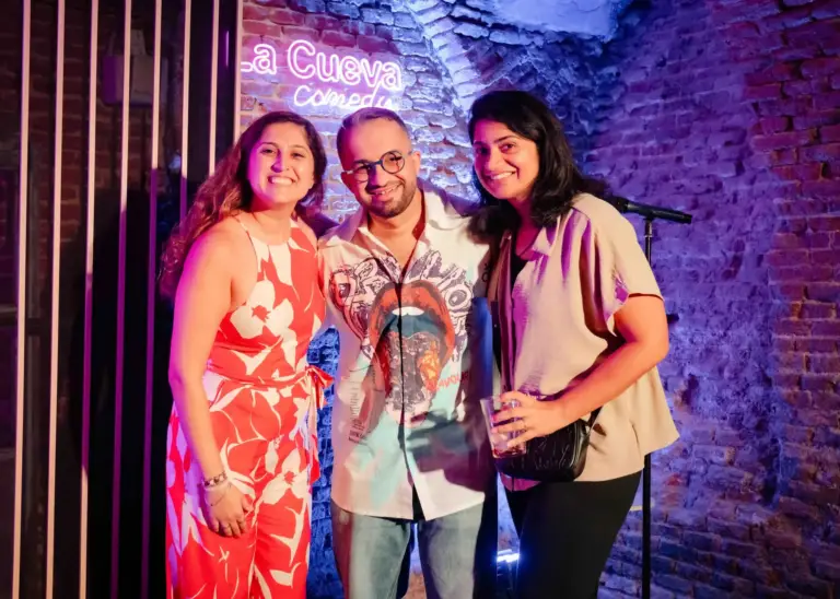 Tres artistas posando juntos bajo el rótulo de La Cueva Comedy
