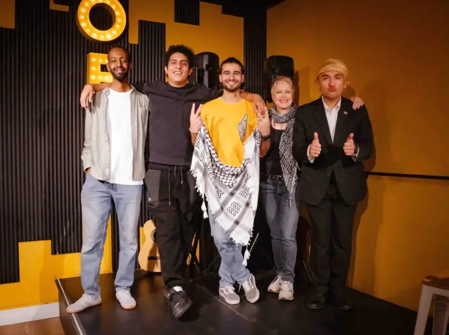Cinco artistas posando en el escenario delante de las letras iluminadas de OFF
