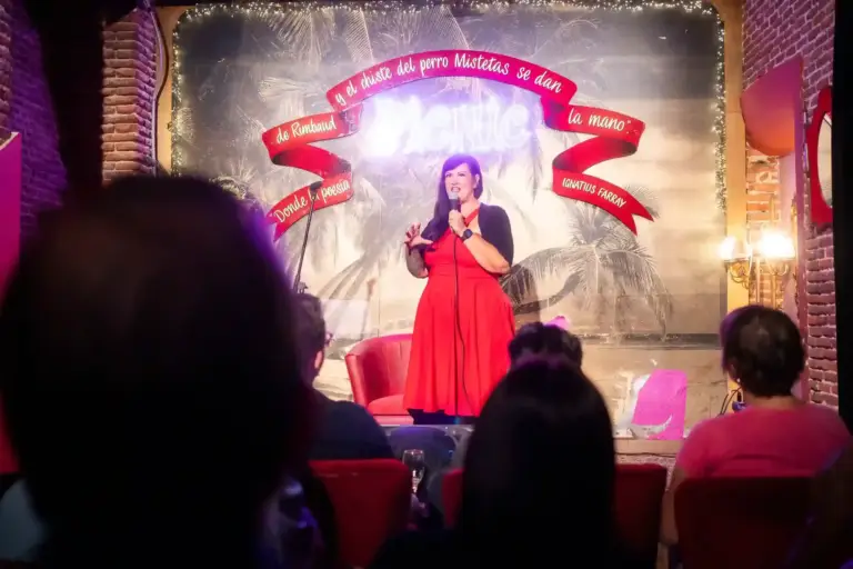 Cómica con vestido rojo en el escenario de Picnic, vista desde el fondo de la sala