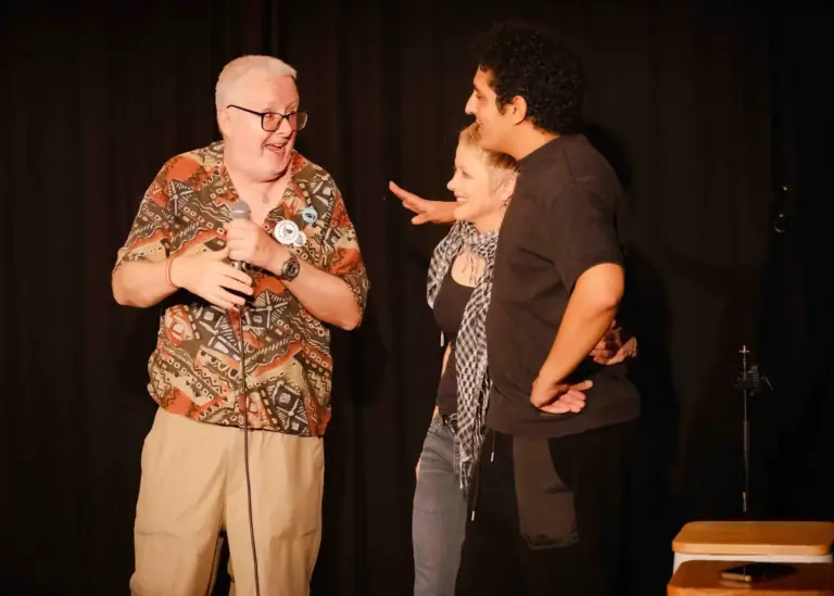 Tres artistas riéndose juntos en el escenario
