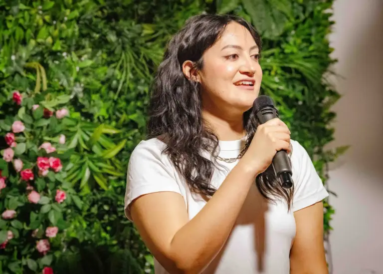 Cómica con camiseta blanca hablando al micrófono en Tropicana